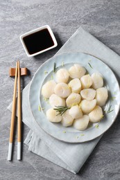Photo of Raw scallops with lemon zest, rosemary and soy sauce on grey marble table, flat lay