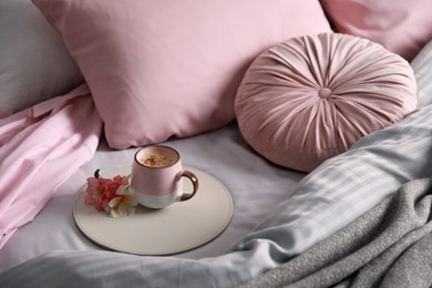 Aromatic coffee and beautiful flowers on bed with fresh linens