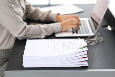 Photo of Businesswoman working with laptop at table in office, focus on documents