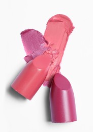 Photo of Different bright lipsticks and smears on white background, top view