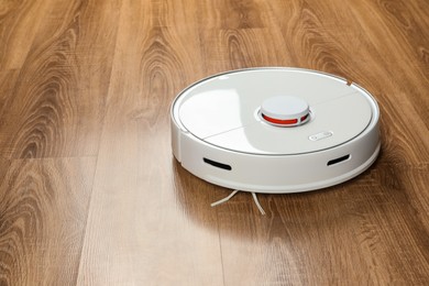 Photo of Robotic vacuum cleaner on wooden floor, space for text