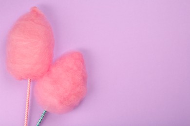 Photo of Two sweet pink cotton candies on lilac background, flat lay. Space for text