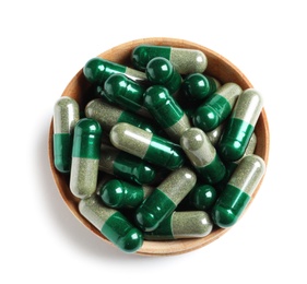 Photo of Wooden bowl with green spirulina capsules on white background, top view