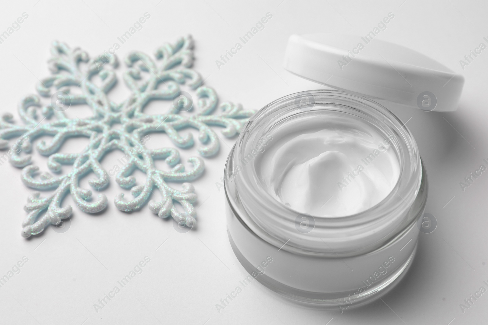 Winter skin care. Hand cream and decorative snowflake on white background, closeup Photo of Winter skin care. Hand cream and decorative snowflake on white background, closeup