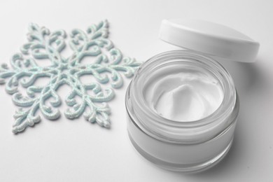 Photo of Winter skin care. Hand cream and decorative snowflake on white background, closeup