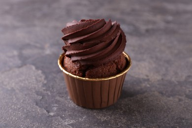 Photo of Delicious chocolate cupcake on grey textured table, closeup