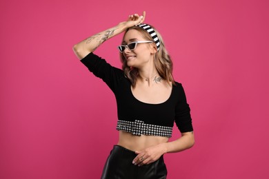 Photo of Beautiful woman with tattoos on body against pink background