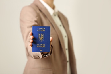 Photo of Woman holding Ukrainian travel passport on light background, closeup with space for text. International relationships