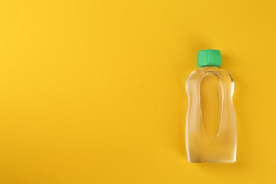 Photo of Bottle with baby oil on orange background, top view. Space for text