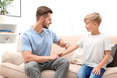 Photo of Young man checking little boy's pulse indoors