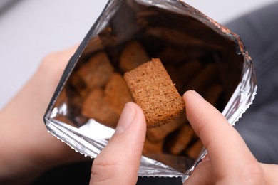 Photo of Woman taking crispy rusk out of package, closeup