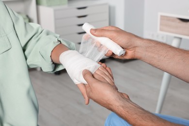 Photo of Doctor applying bandage onto patient's hand in hospital, closeup