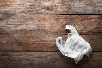 Photo of Clear disposable plastic bag on wooden background. Space for text