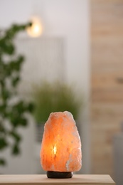 Photo of Himalayan salt lamp on table against blurred background