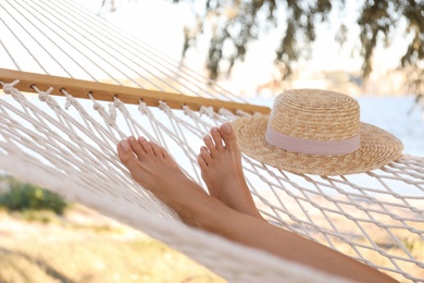 Photo of Young woman relaxing in hammock on beach, closeup. Summer vacation