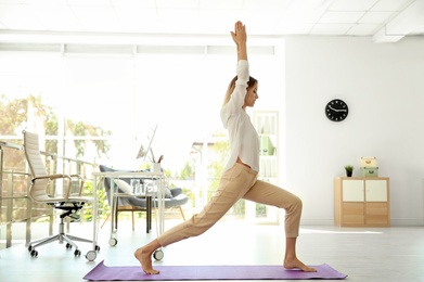 Young businessman doing yoga exercises in office. Workplace fitness