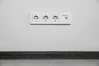 Photo of Power sockets on white wall indoors. Electrical supply
