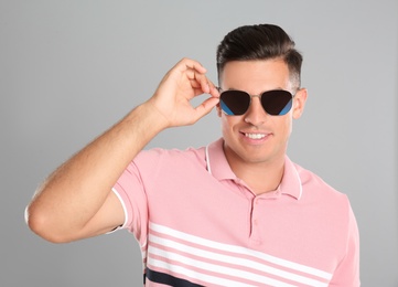 Photo of Handsome man wearing sunglasses on grey background