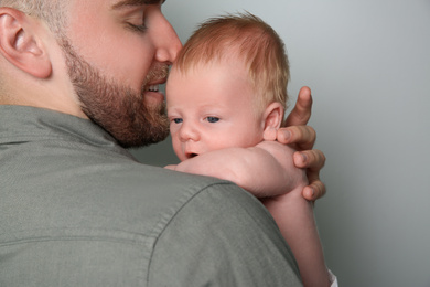 Photo of Father with his newborn son on light grey background, closeup