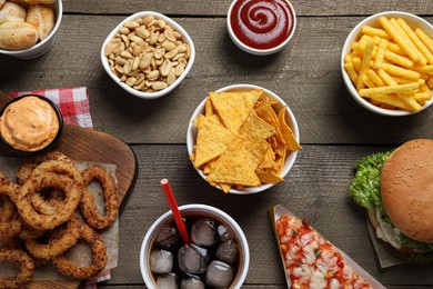 Photo of French fries, onion rings and other fast food on wooden table, flat lay