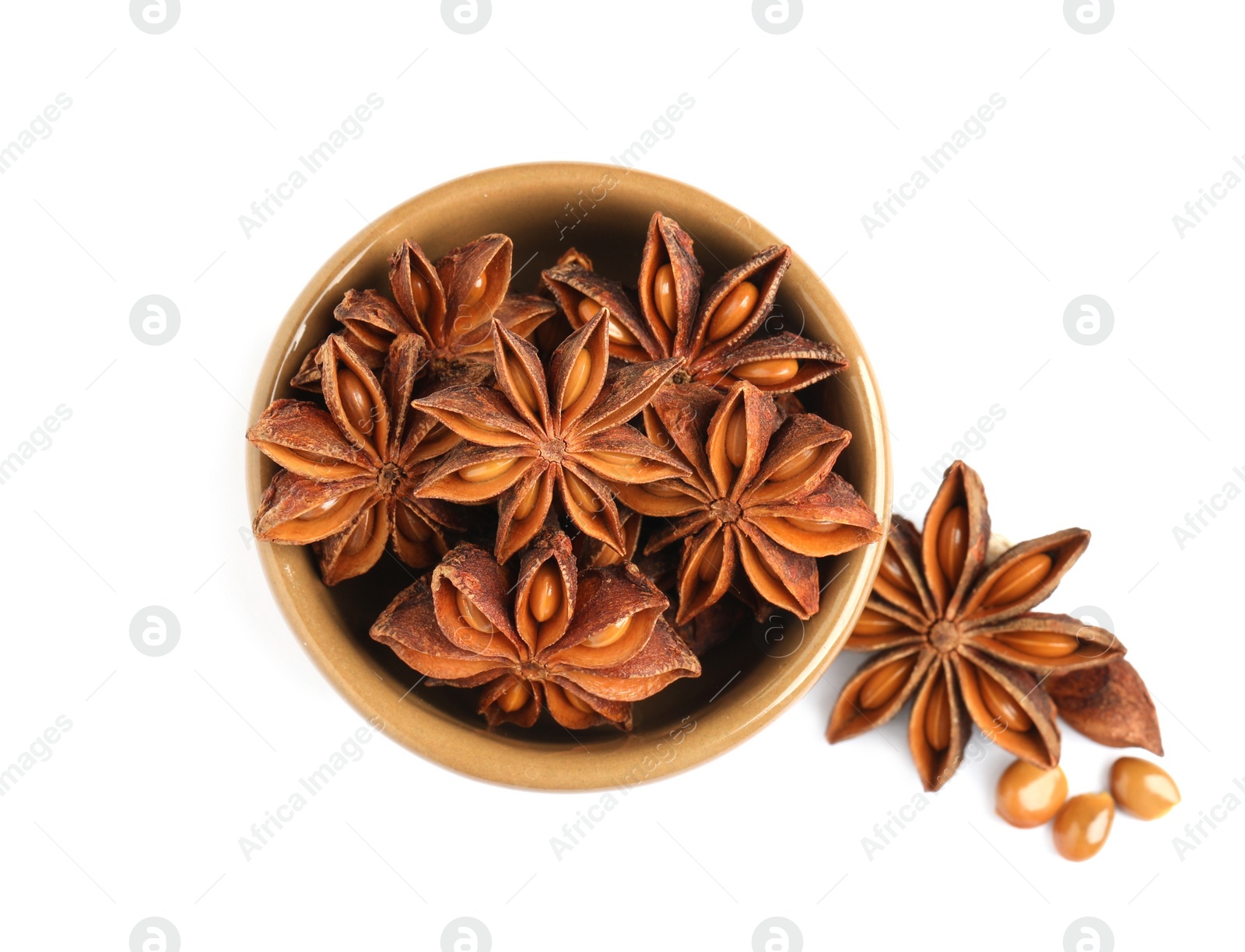 Photo of Bowl and dry anise stars on white background, top view