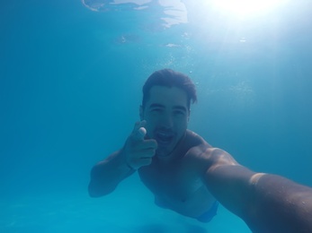 Photo of Handsome young man swimming in pool, underwater view