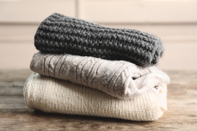 Photo of Stack of warm knitted clothes on table