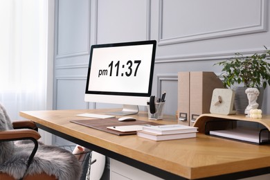 Photo of Stylish workplace with computer, houseplant and stationery on wooden desk near grey wall at home