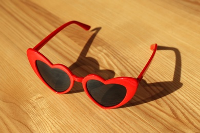 Photo of Stylish heart shaped sunglasses on wooden background