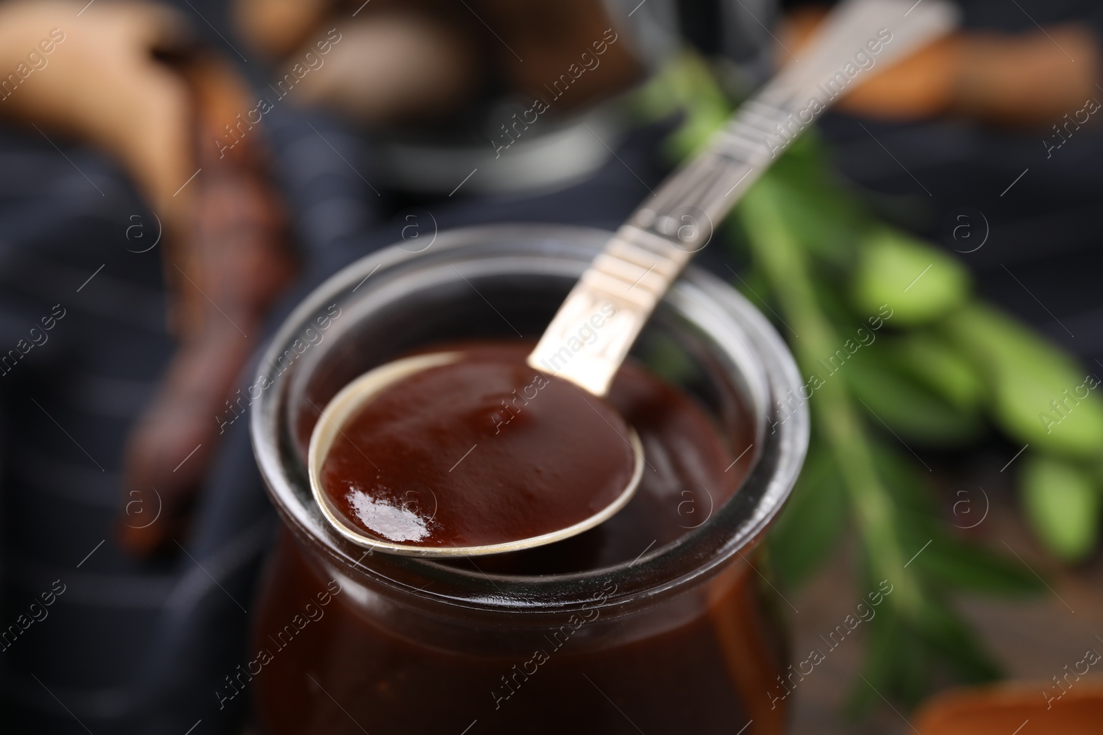 Jar and spoon of tasty tamarind sauce on table, closeup Photo of Jar and spoon of tasty tamarind sauce on table, closeup