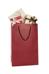 Photo of Paper shopping bag full of gift boxes isolated on white