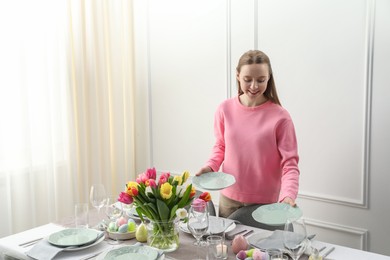 Photo of Woman setting table for festive Easter dinner at home