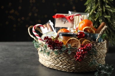 Photo of Wicker basket with gift set and Christmas decor on grey table. Space for text