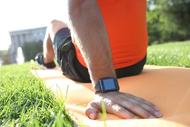 Photo of Man with fitness tracker after training in park, closeup