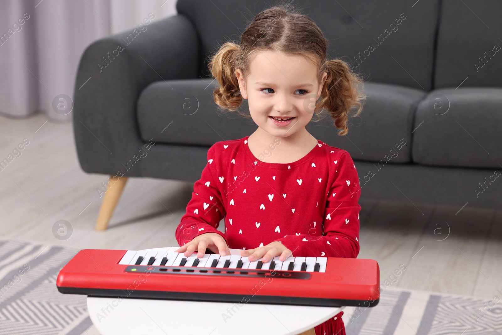 Photo of Little girl playing toy piano at home