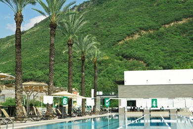 Photo of Outdoor swimming pool at luxury resort and beautiful view of mountains on sunny day