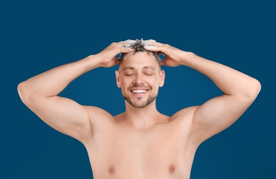 Photo of Handsome man washing hair on blue background