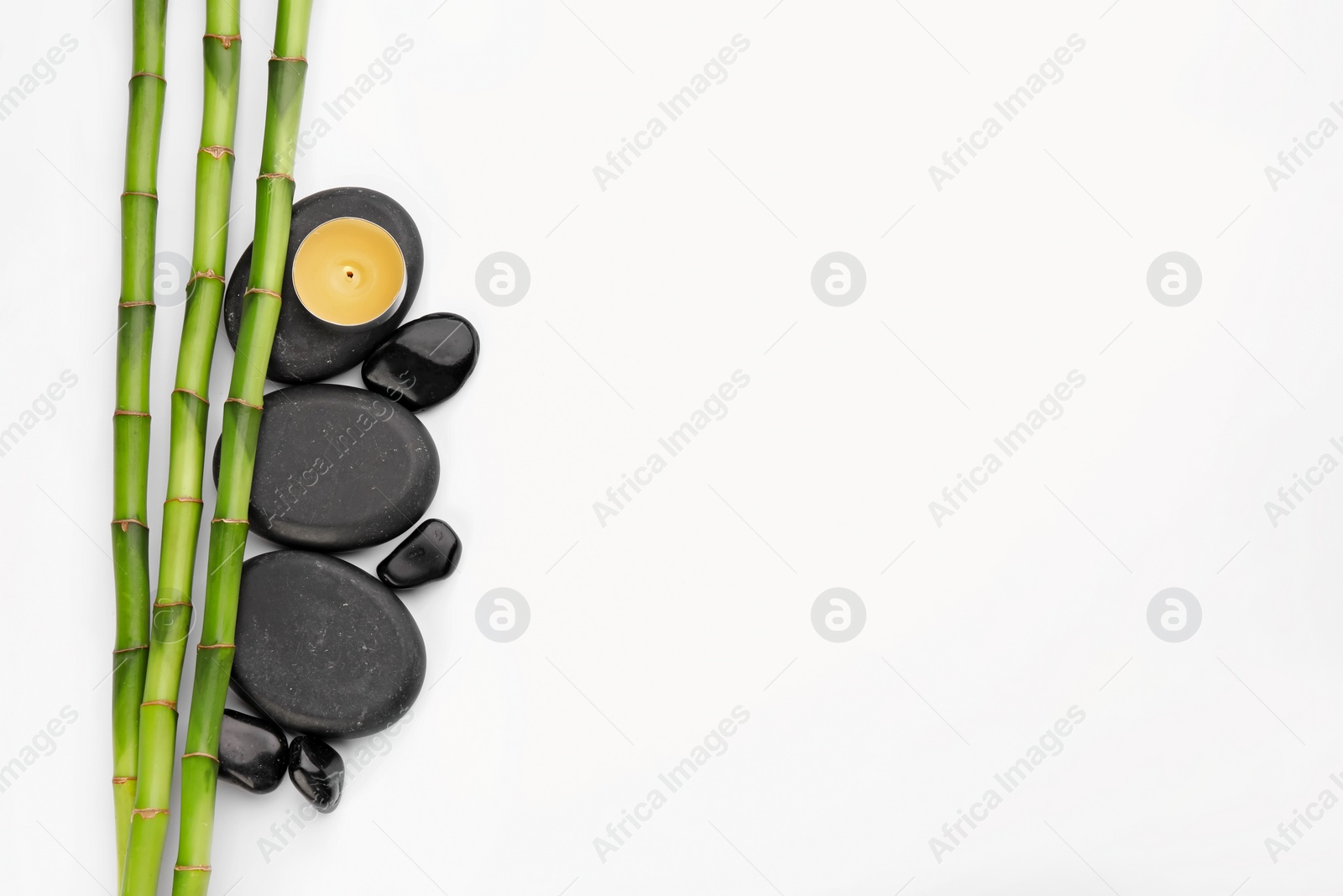 Photo of Spa stones, candle and bamboo stems on white background, top view