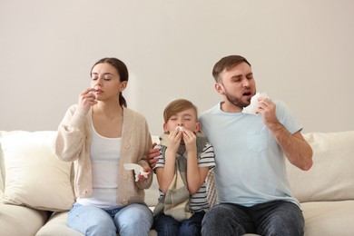 Photo of Family suffering from runny nose on sofa at home