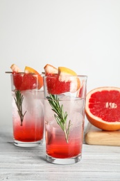 Photo of Glasses of cocktail and grapefruit half on table. Space for text