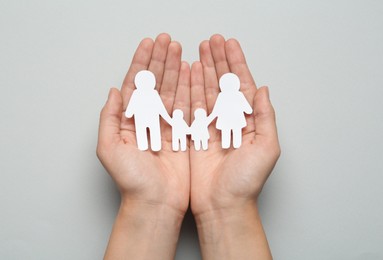Photo of Woman holding paper family cutout on light grey background, top view