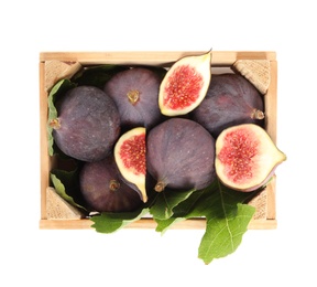 Photo of Whole and cut tasty fresh figs with green leaves in wooden crate on white background, top view