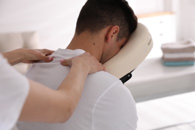 Photo of Man receiving massage in modern chair indoors, closeup