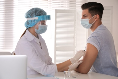 Photo of Doctor vaccinating man against Covid-19 in clinic