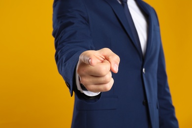 Photo of Businessman touching something on yellow background, closeup. Finger gesture