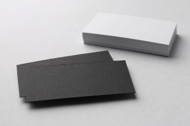Photo of Blank black and white business cards on light background, closeup. Mockup for design
