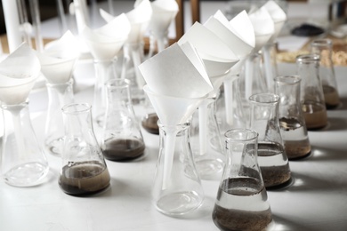 Photo of Laboratory glassware with soil extracts and funnels on table