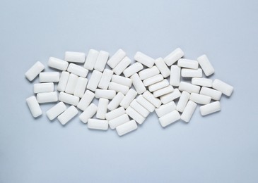 Photo of Tasty white chewing gums on light grey background, flat lay