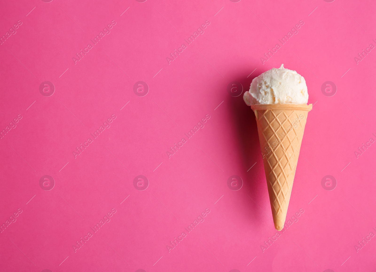 Photo of Waffle cone with tasty vanilla ice cream on color background