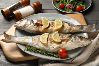 Photo of Delicious baked fish served on grey wooden table
